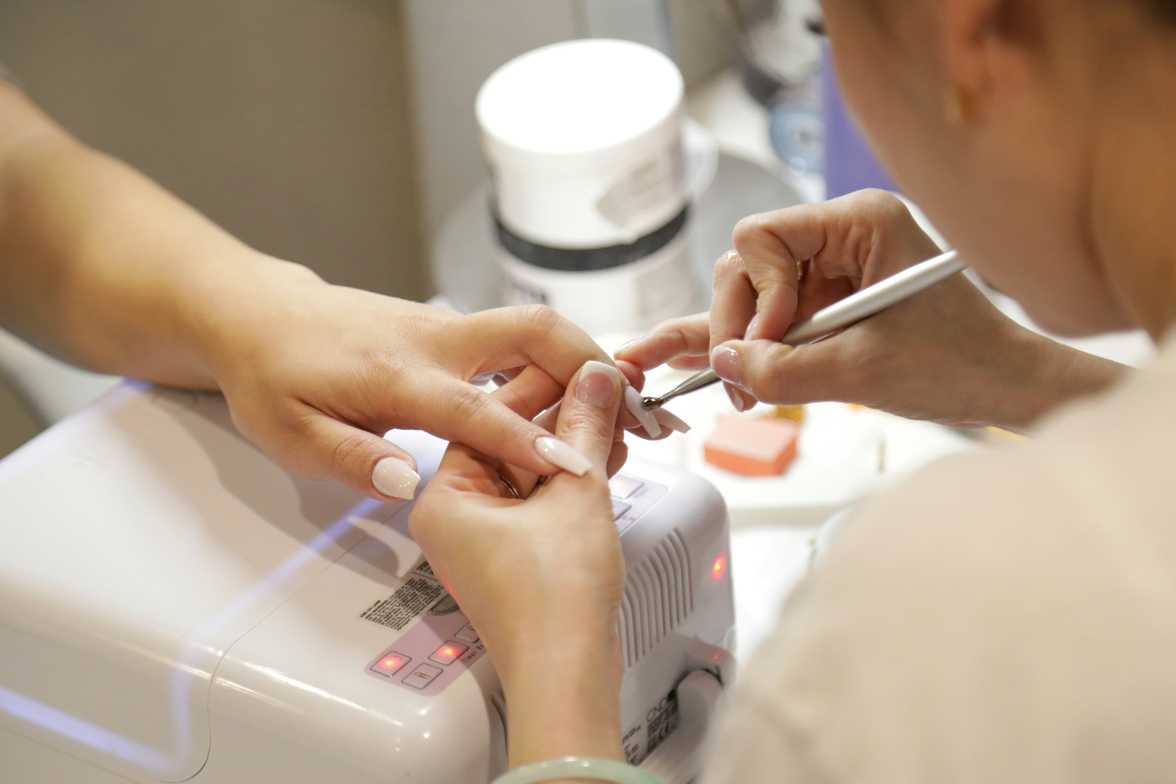 Nail technician shaping a client's nails at the manicure desk