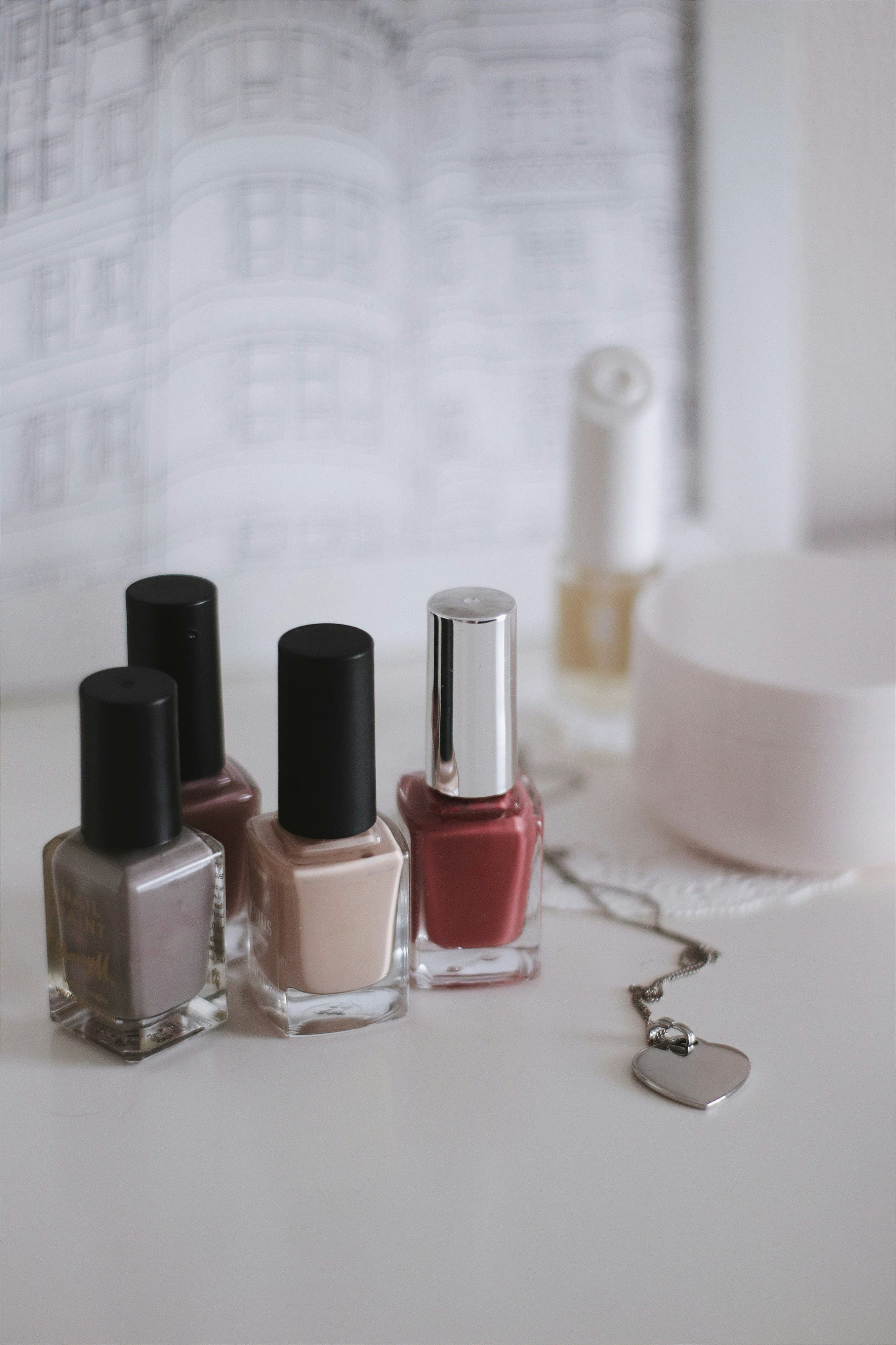 Nude, grey and berry nail polish bottles on a white table
